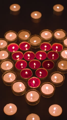 Vertical-Video-Of-Romantic-Red-And-White-Candles-In-the-Shape-Of-A-Heart-On-Black-Background-2